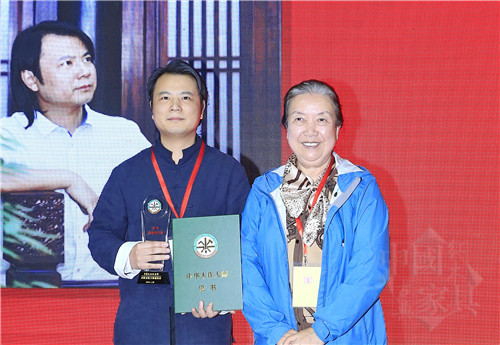 01中華兒童藝術促進會會長范崇嬿(右)為石華久(左)頒授“中華木作大師”榮譽